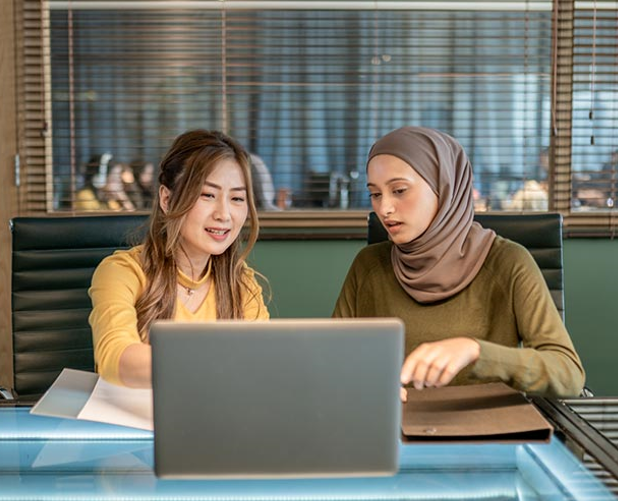 Woman with black curly hair wearing a backpack in a hallway holding and about to tap a phone